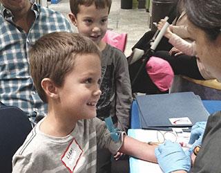 Niño sonriendo a la enfermera mientras se extrae sangre