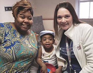 Una madre y su pequeño hijo sonriendo con un miembro de TrialNet