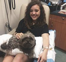 Girl having blood drawn with a small dog on her lap