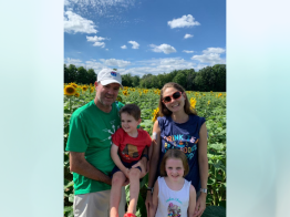  TrialNet participant Amanda Gilchrist along with her spouse and two young children pause for a family picture in a field of yellow sunflowers