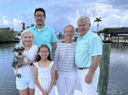 DECA Executive Director Terry posing for a photo with family members on a dock: wife, daughter, son-in-law, grandchild, and dog