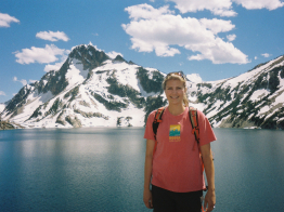 Lisa Gier in the foreground wearing a Camp Hodia shirt with a lake and snow-capped mountain in the background